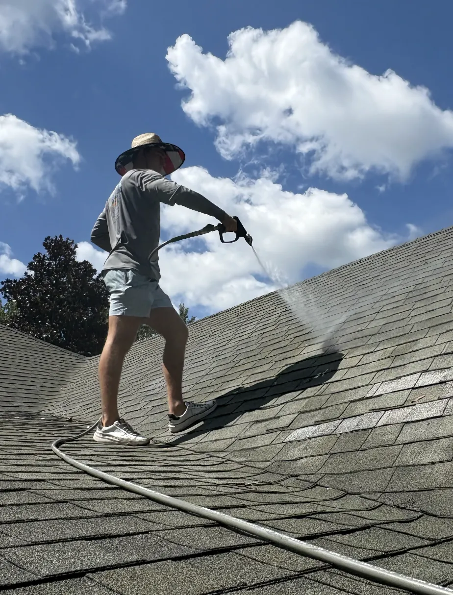 Surf technician soft washing a shingle roof