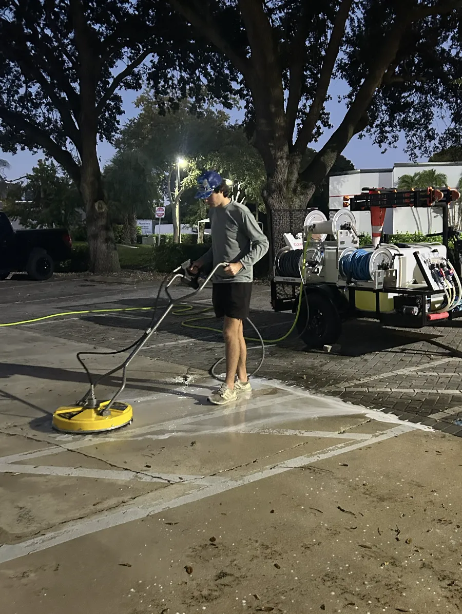Surf technician pressure washing a concrete surface with a surface cleaner