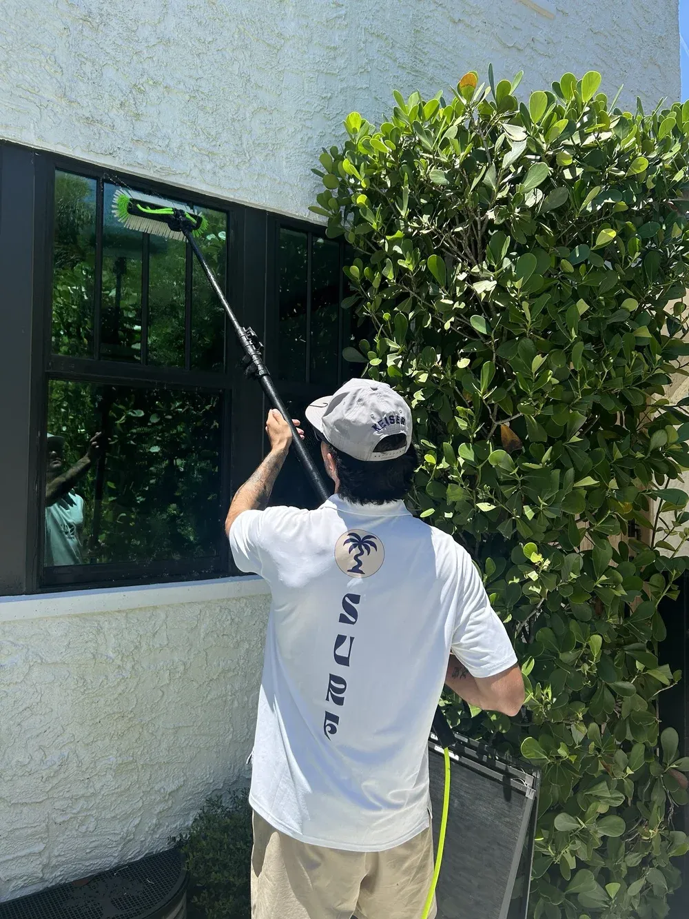 Technician cleaning tall windows with a pole